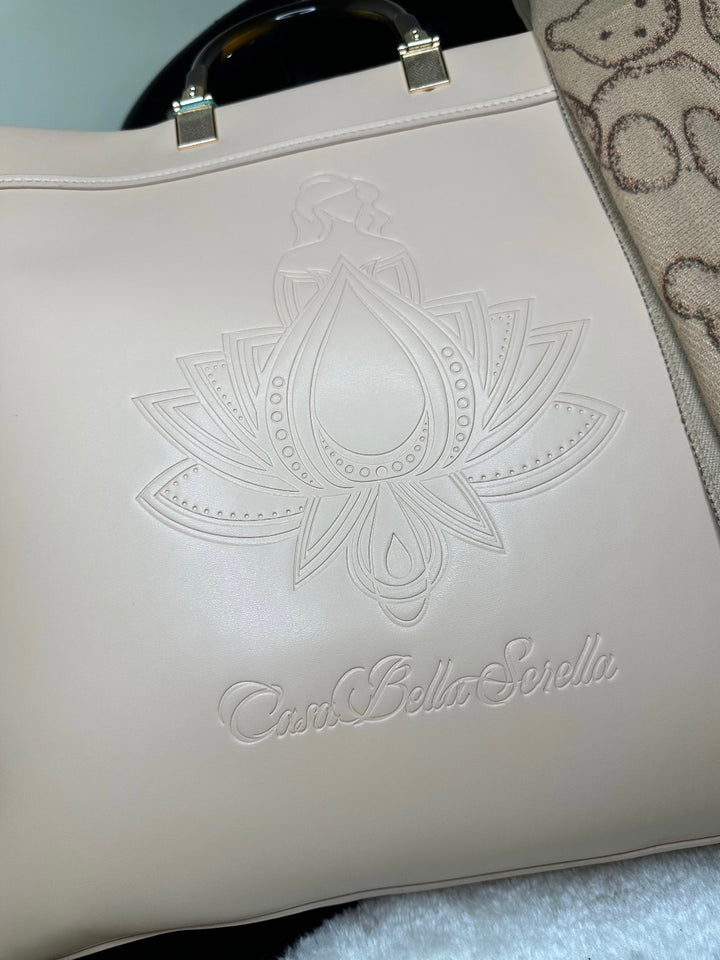 An image showing a beige handbag tote with an embossed cbs logo design, and a scarf. 