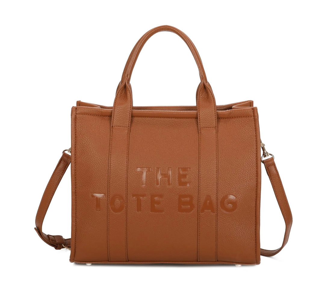A brown tote bag with embossed ‘The Tote Bag’ text, structured design with top handles and detachable shoulder strap