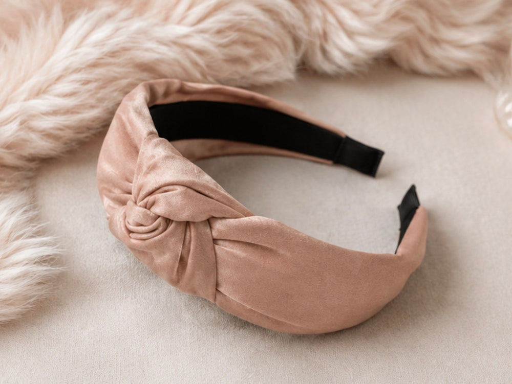 Soft pink satin knotted padded headband with elegant knot detail and comfortable design.