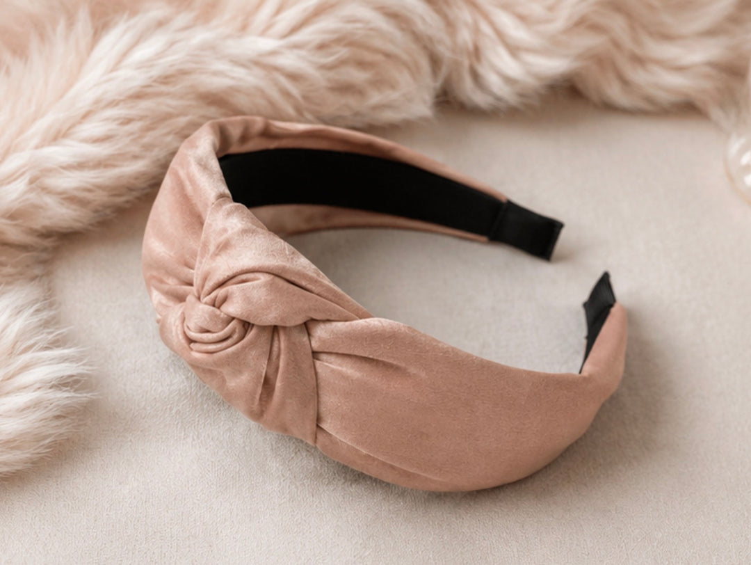 Soft pink satin knotted padded headband with elegant knot detail and comfortable design.