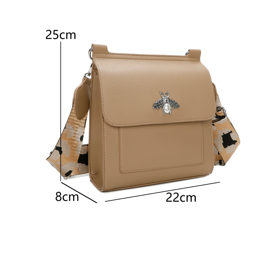 A beige satchel crossbody bag with a bee design on the front flap, featuring a camouflage pattern on the strap.