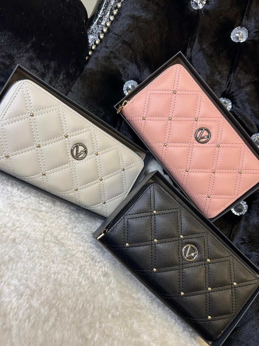 Three quilted leather purses in pink, white, and black, displayed side by side with zip compartments visible.