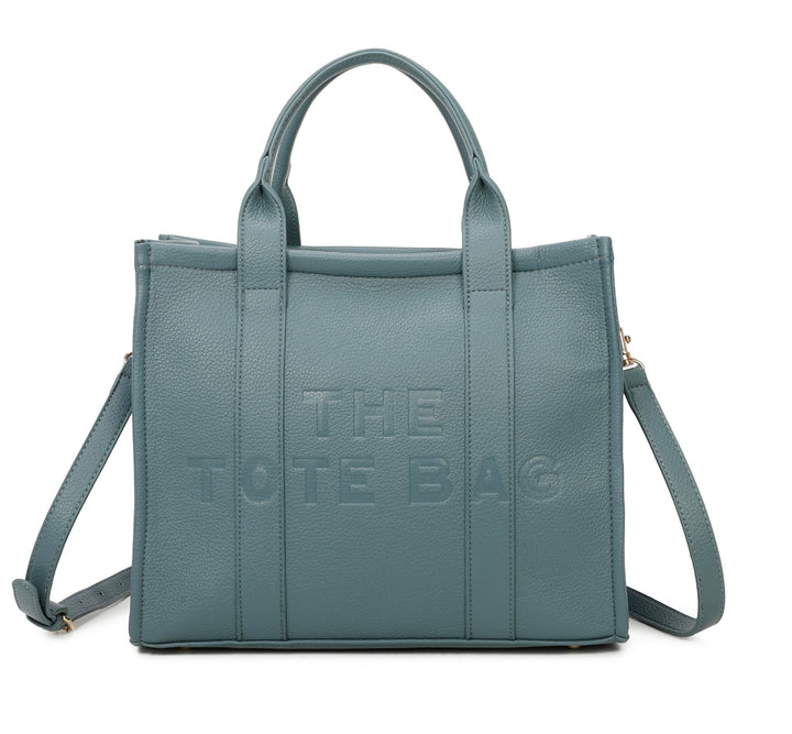 A blue/grey tote bag with embossed ‘The Tote Bag’ text, structured design with top handles and detachable shoulder strap