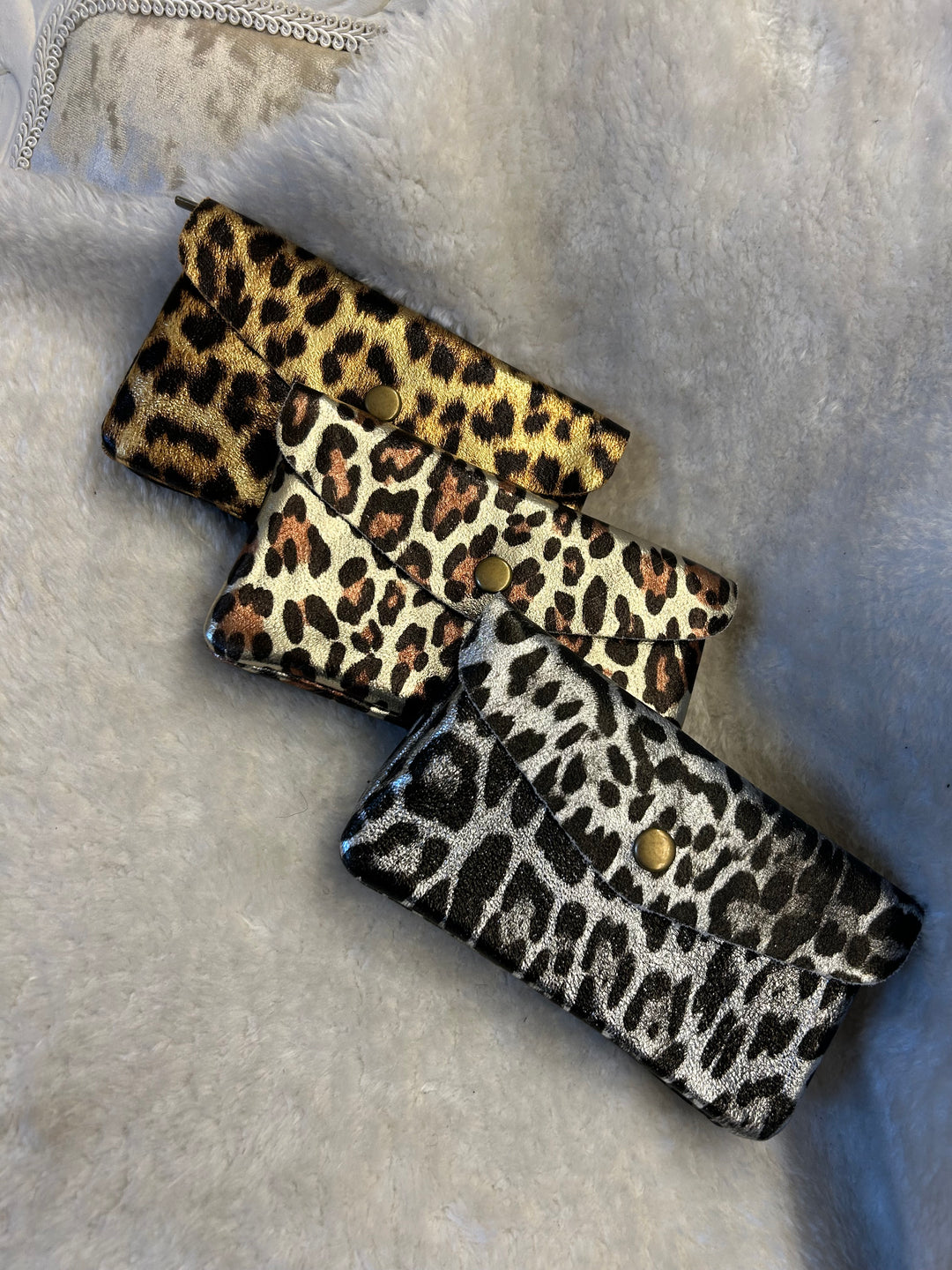 A collection of real leather purses with leopard print patterns in various colors.
