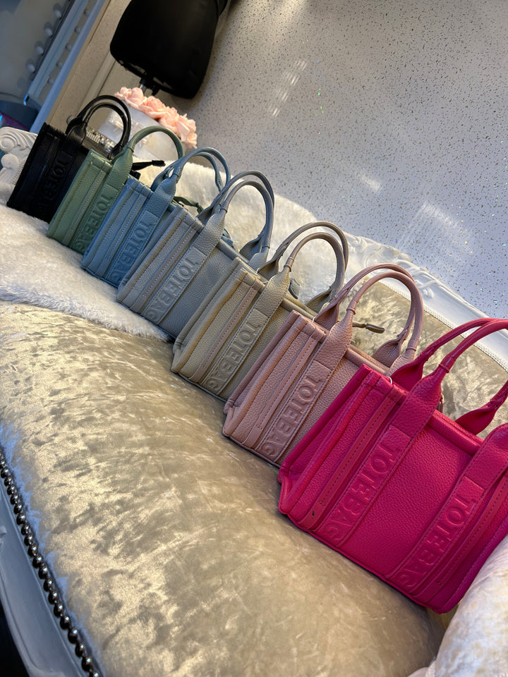 A collection of stripe dinky dot tote bags, with colours including green, blue, grey, and pink.