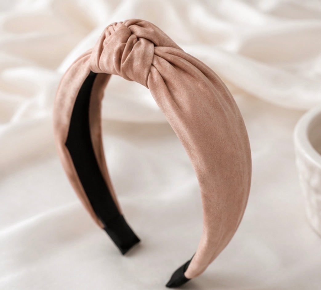 Soft pink satin knotted padded headband with elegant knot detail and comfortable design.