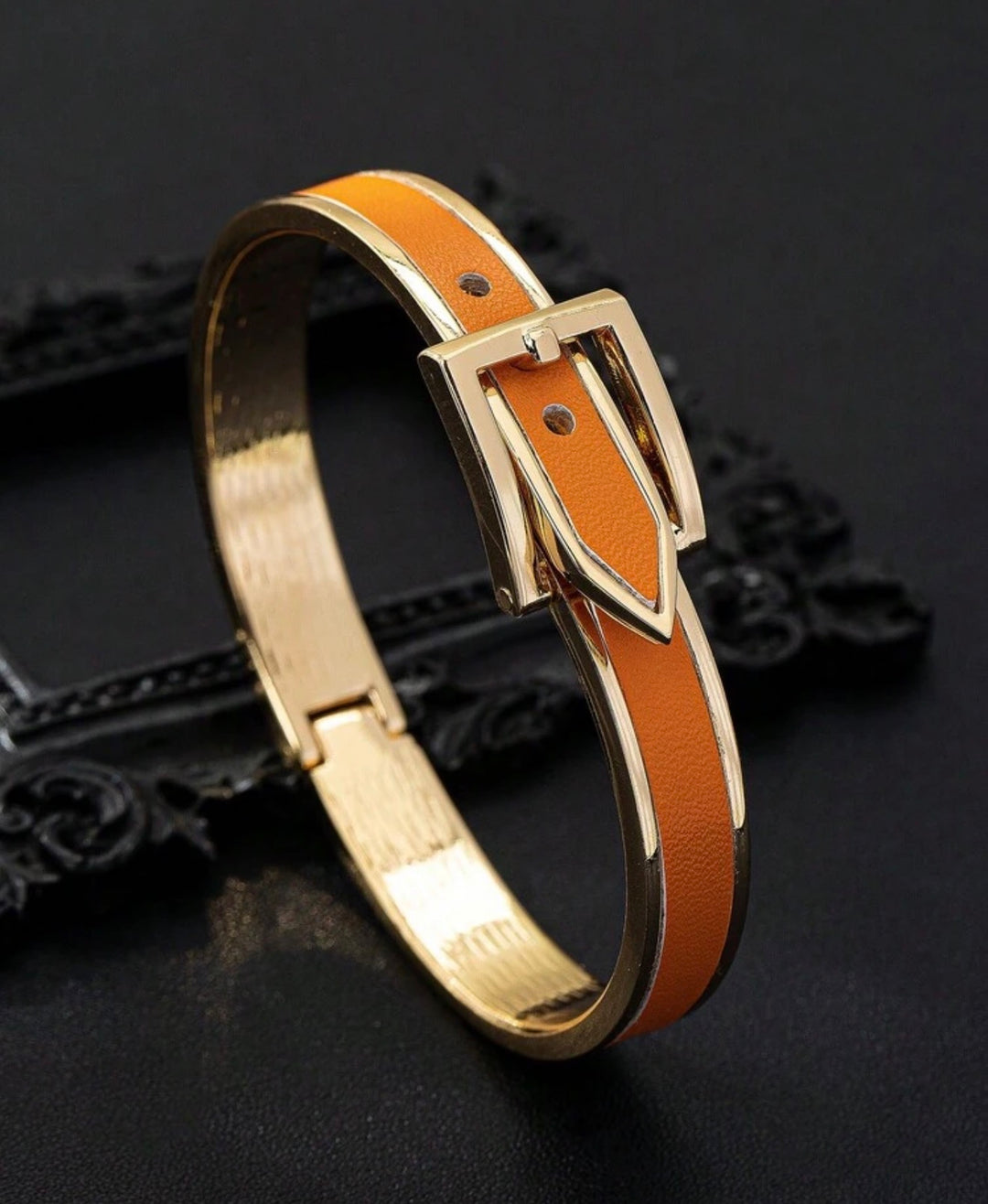     Polished gold buckle cuff bracelet with orange enamel detail