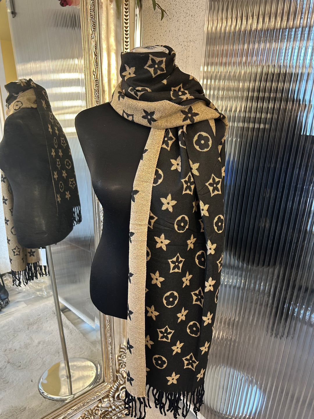 A black scarf with sparkly metallic thread floral patterns, draped elegantly with a focus on the sparkly details.