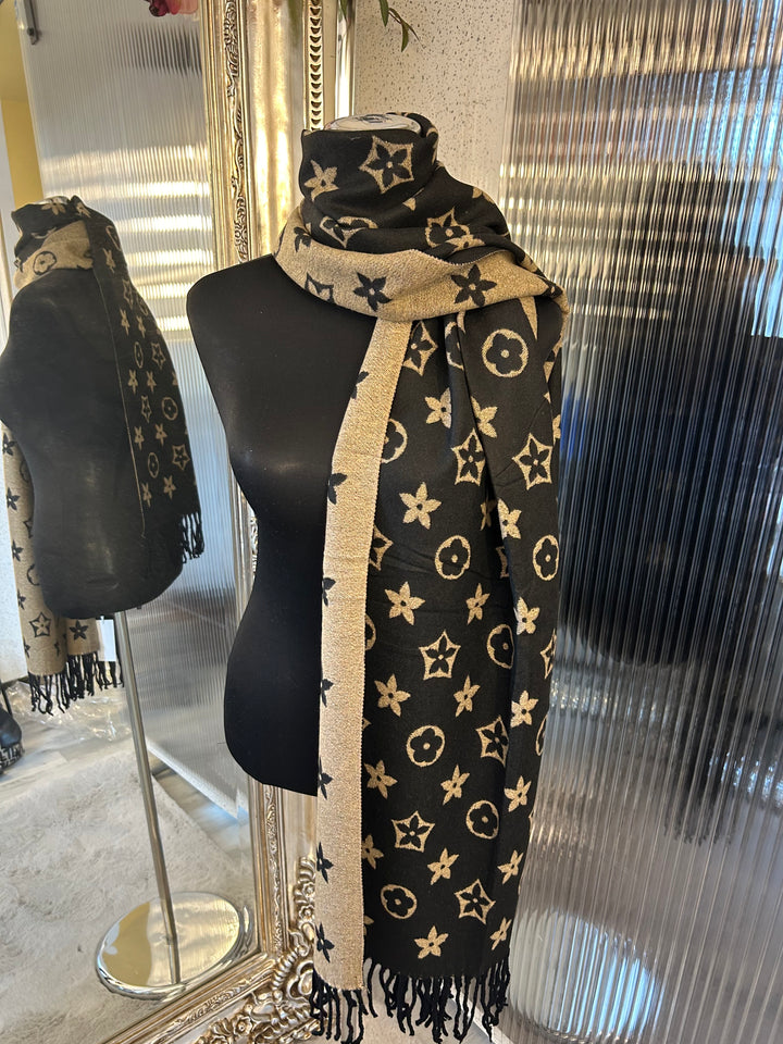 A black scarf with sparkly metallic thread floral patterns, draped elegantly with a focus on the sparkly details.