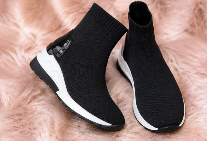 A pair of black and white slip-on trainers with a wedge sole.