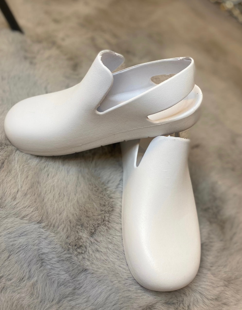 A pair of white slingback clogs 
