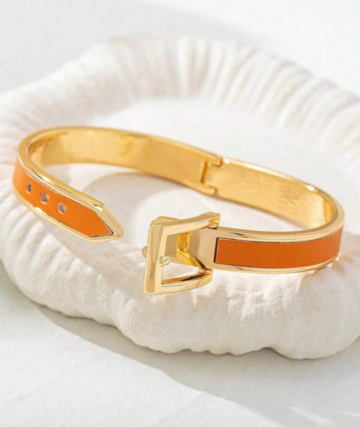     Polished gold buckle cuff bracelet with orange enamel detail