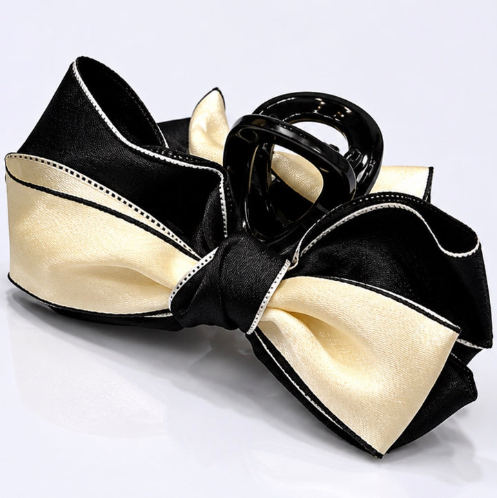 Black and cream satin bow hair clip with contrasting trim detail and glossy claw clip fastening