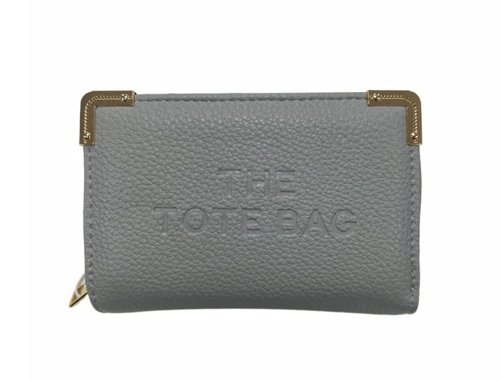 A grey synthetic tote bag with gold tone metal hardware, featuring a fold-over top with a closure, and the ‘THE TOTE BAG&