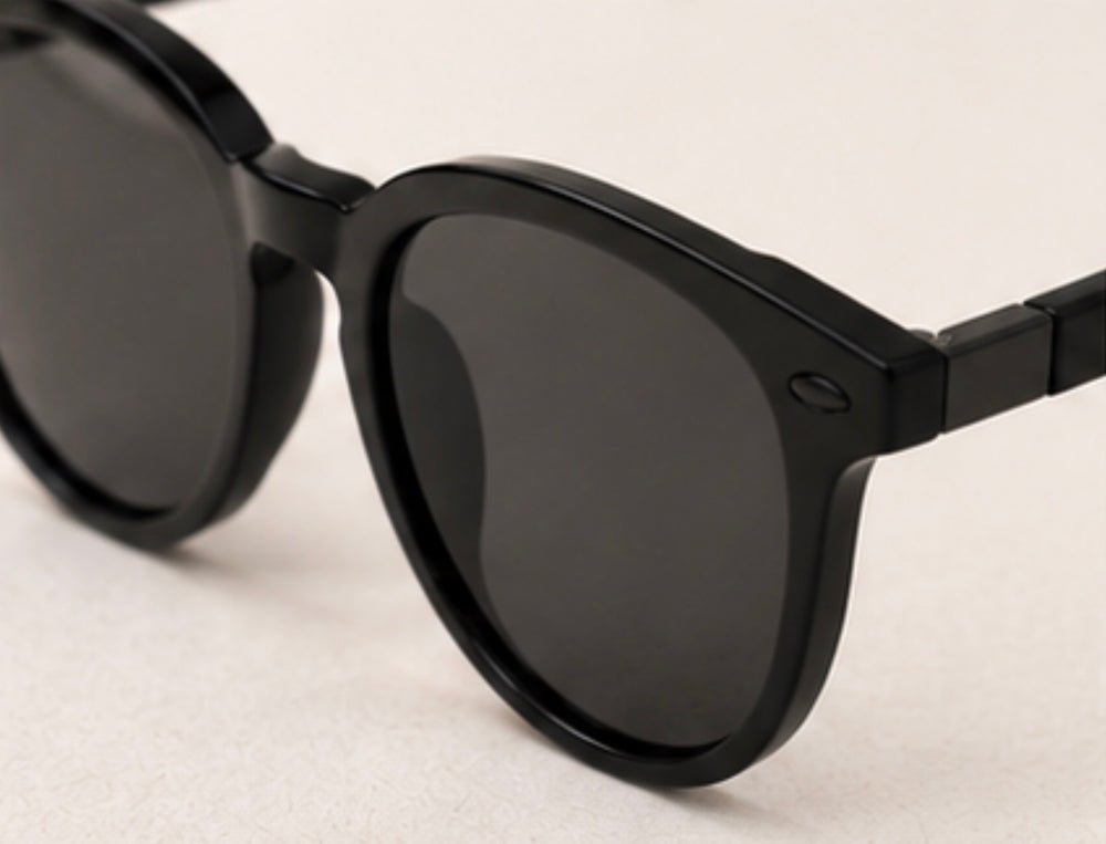 Black round frame sunglasses with dark tinted lenses and black hardware detail