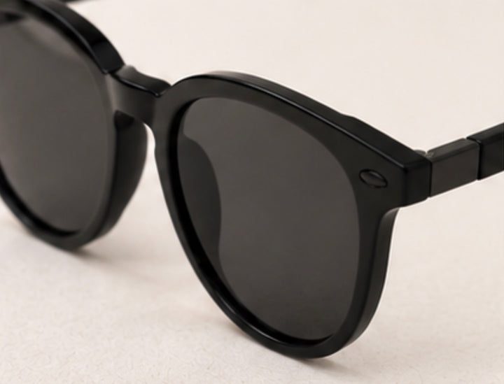 Black round frame sunglasses with dark tinted lenses and black hardware detail