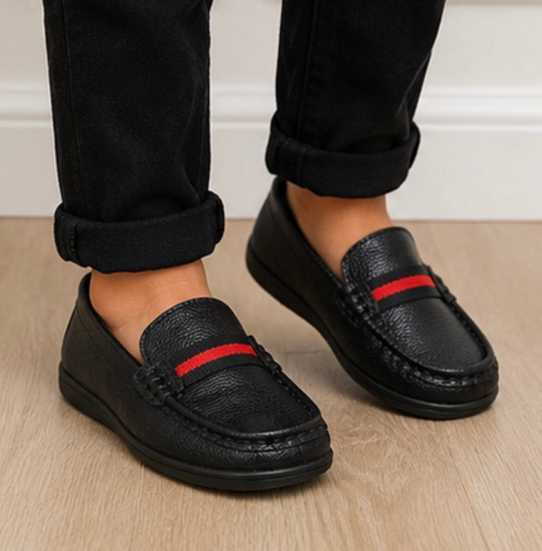 Black kids slip-on loafers with textured faux leather finish and red stripe detail
