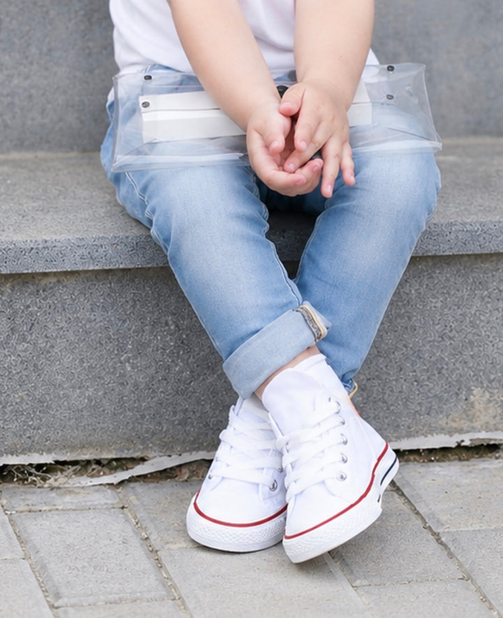 White kids canvas trainers with lace-up fastening and classic chunky sole design.