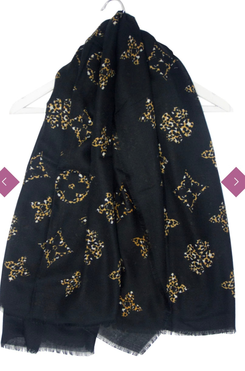 A black scarf with gold and black floral motifs