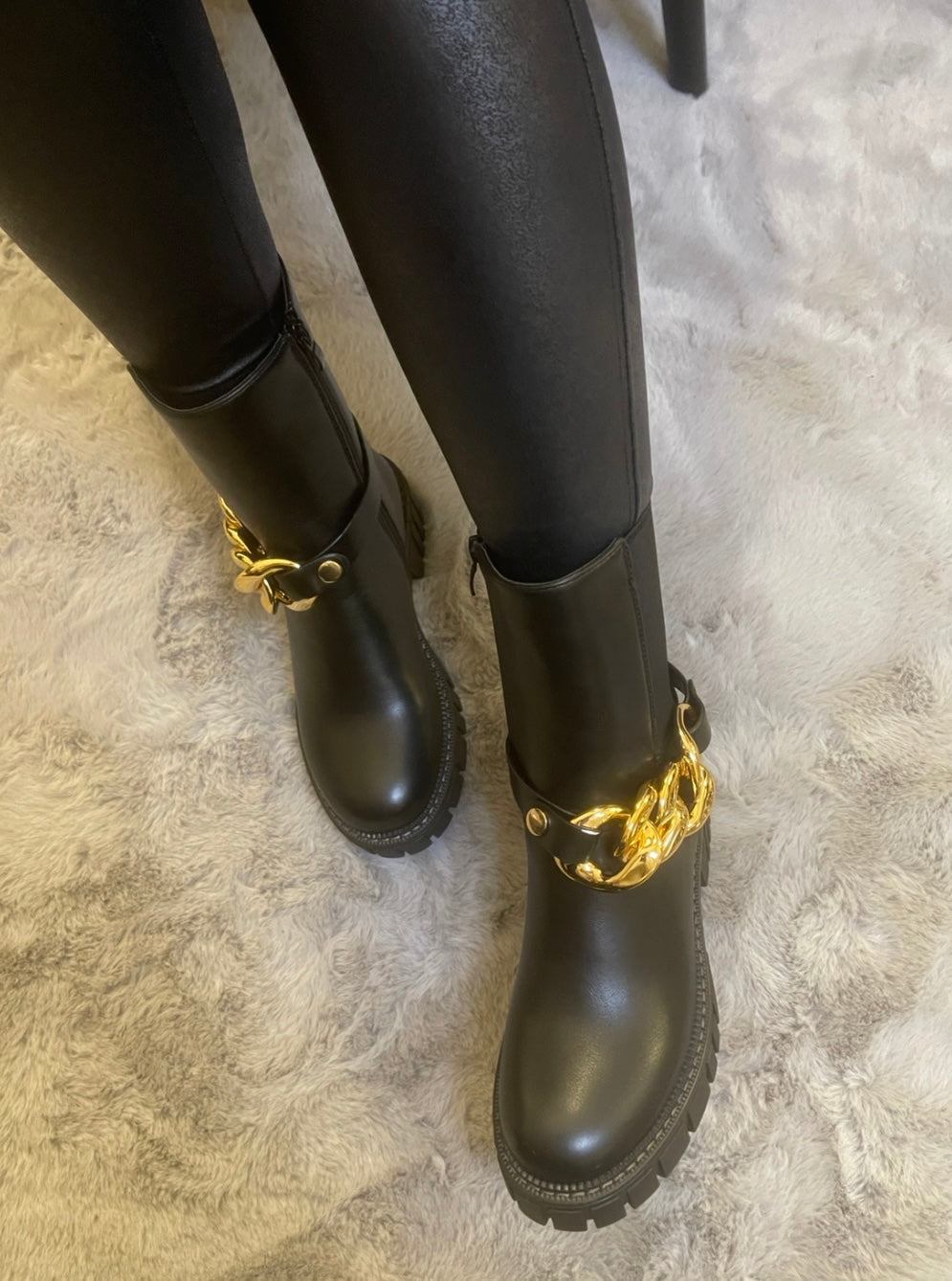 Black chunky ankle boots with gold chain detail worn on feet, stylish women’s boots

