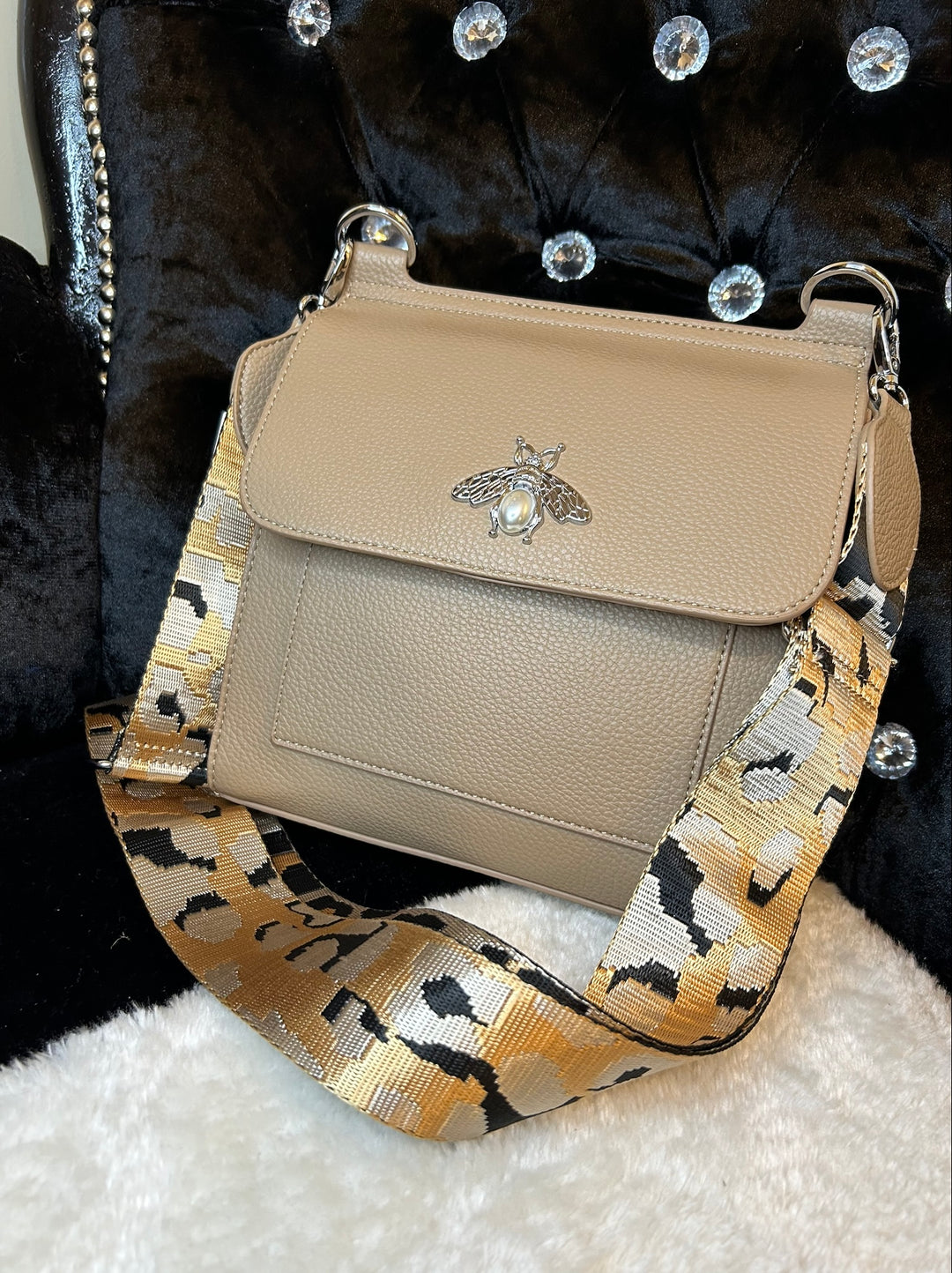 Beige crossbody bag with silver bee and pearl detail on flap, adjustable monochrome patterned straw