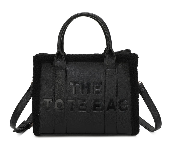 Tote bags with fuzzy edge trim, embossed with ‘The Tote Bag’ on the front in black 