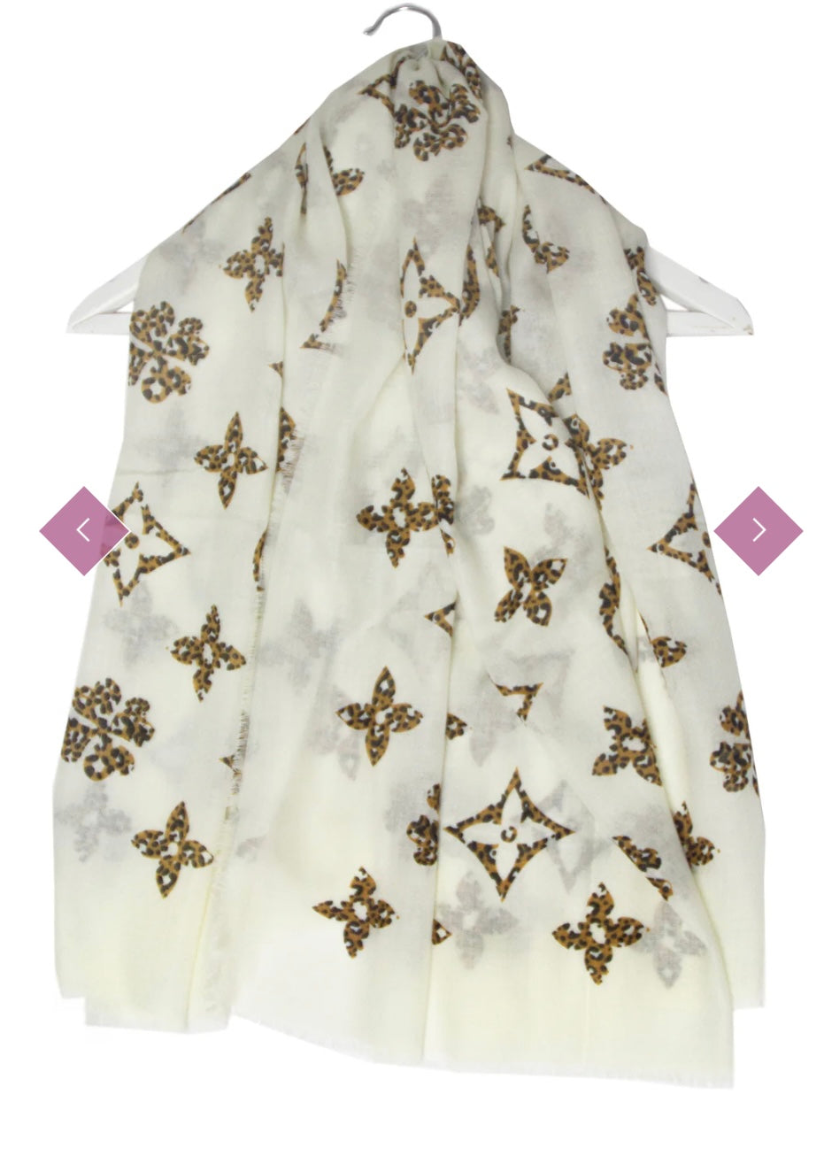 A white scarf with gold and black floral motifs