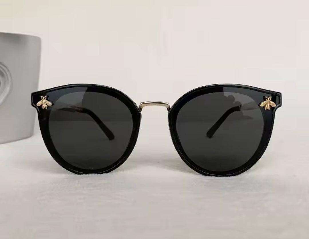 Black sunglasses with gold bee embellishment and green red stripe arms