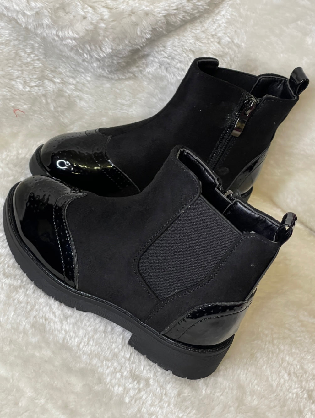 A pair of black ankle boots for girls with a glossy finish