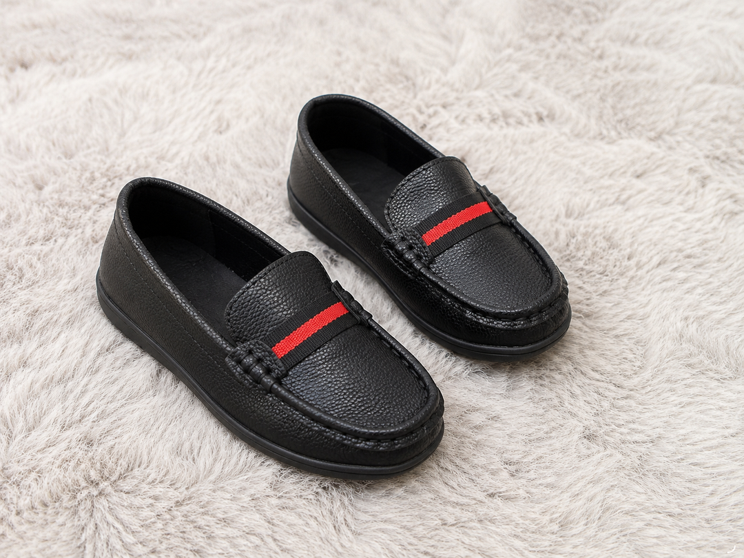 Black kids slip-on loafers with textured faux leather finish and red stripe detail