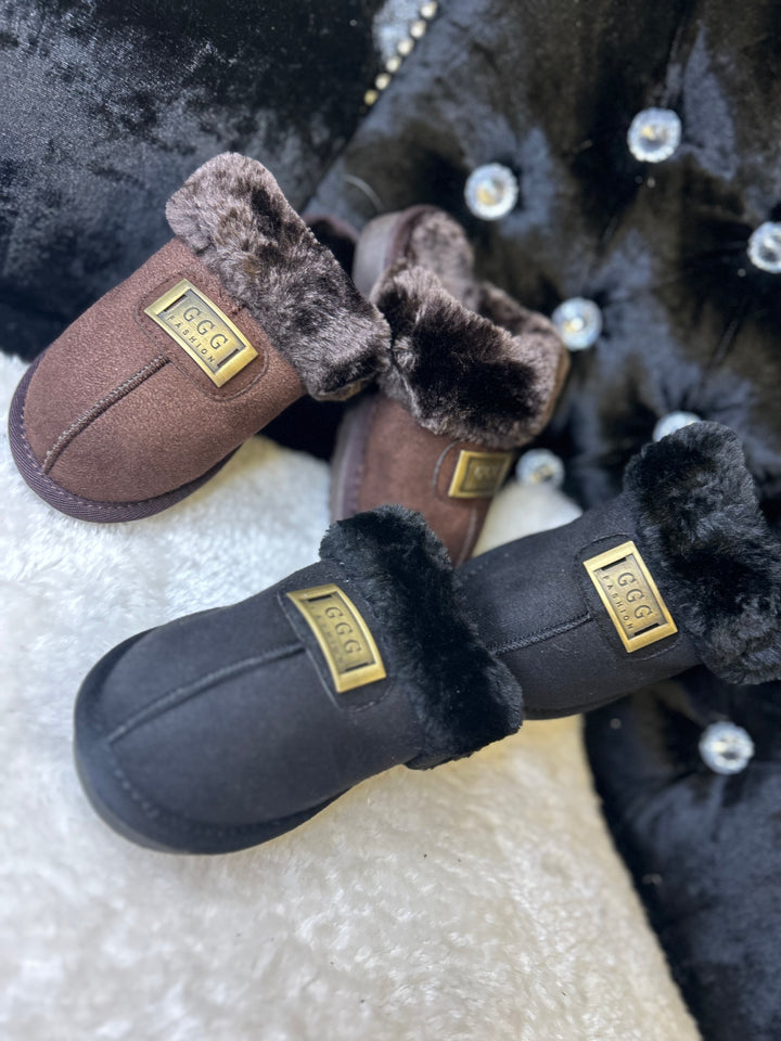 a choice of chocolate brown or black closed toe slip on faux fur slippers with gold buckle on the front