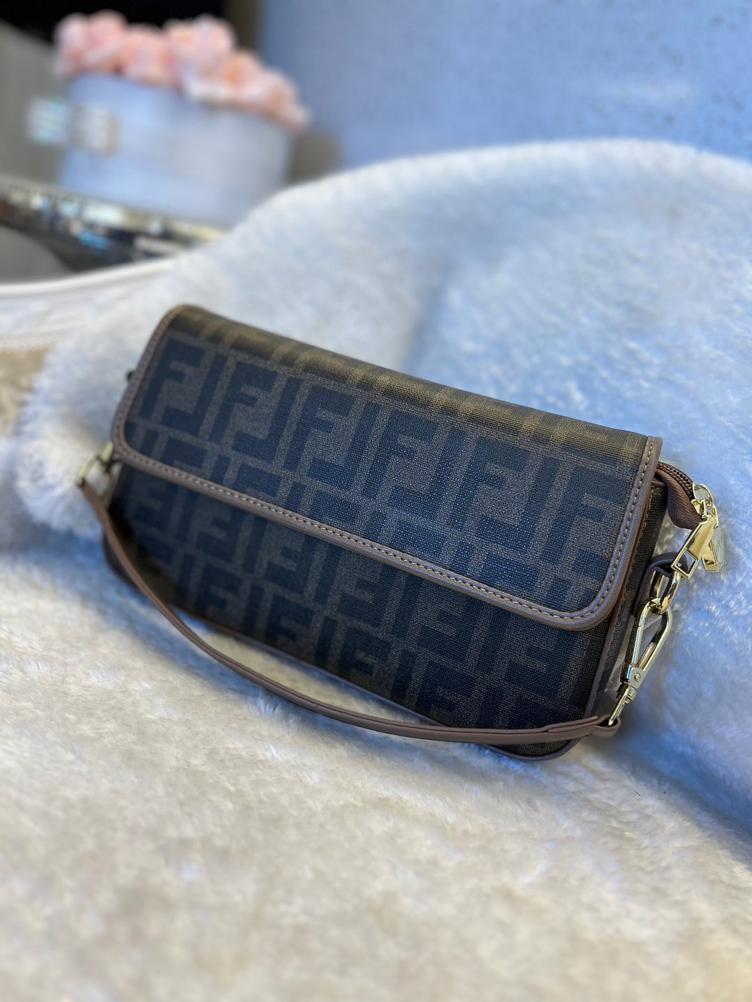 Brown handbag with shoulder strap on a textured surface