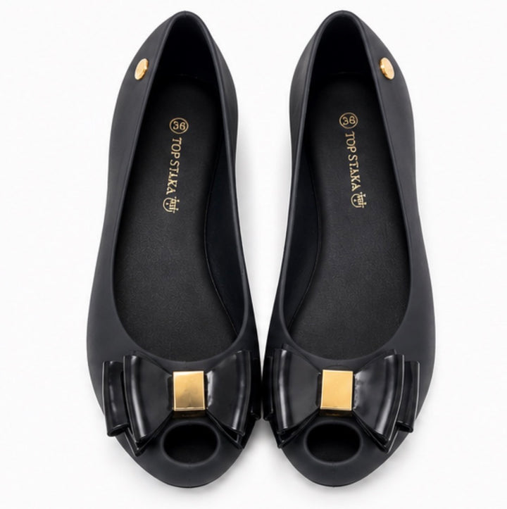 Women’s black jelly-style flats with decorative bow front