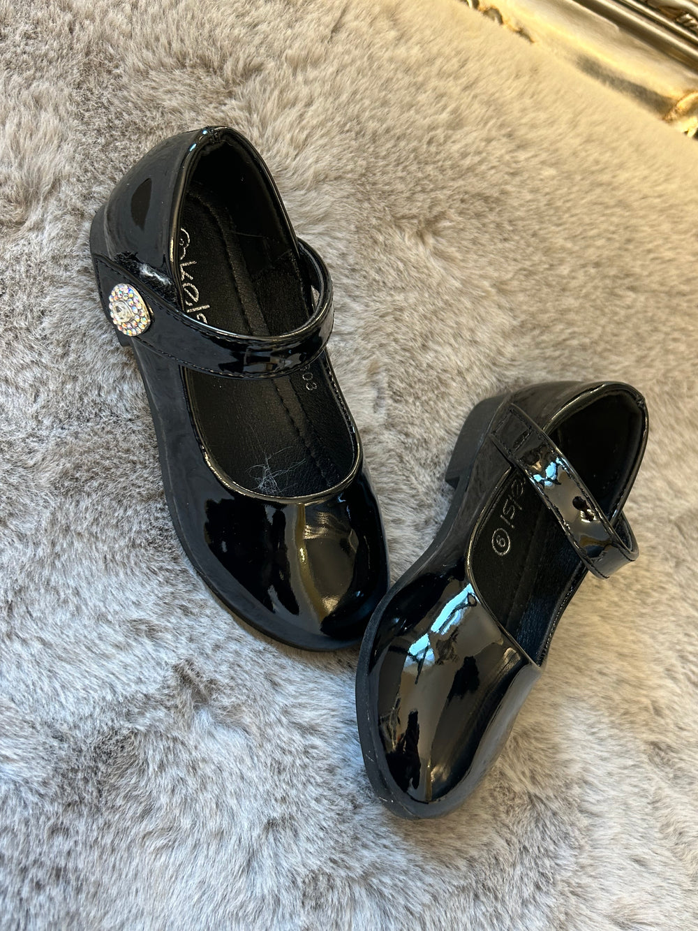 A pair of black, patent leather little girl's school shoes with crystal detailing, 