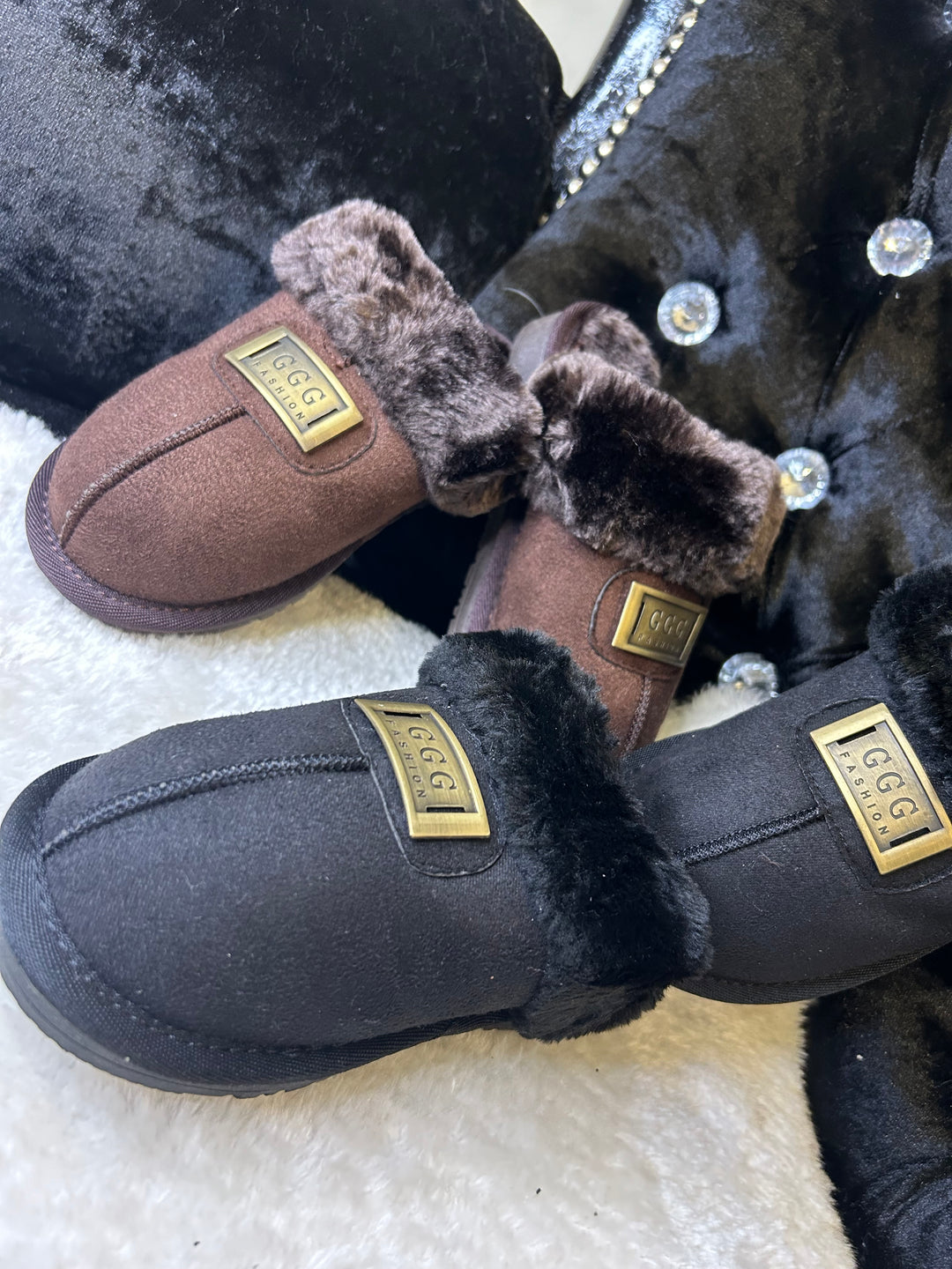 a choice of chocolate brown or black closed toe slip on faux fur slippers with gold buckle on the front