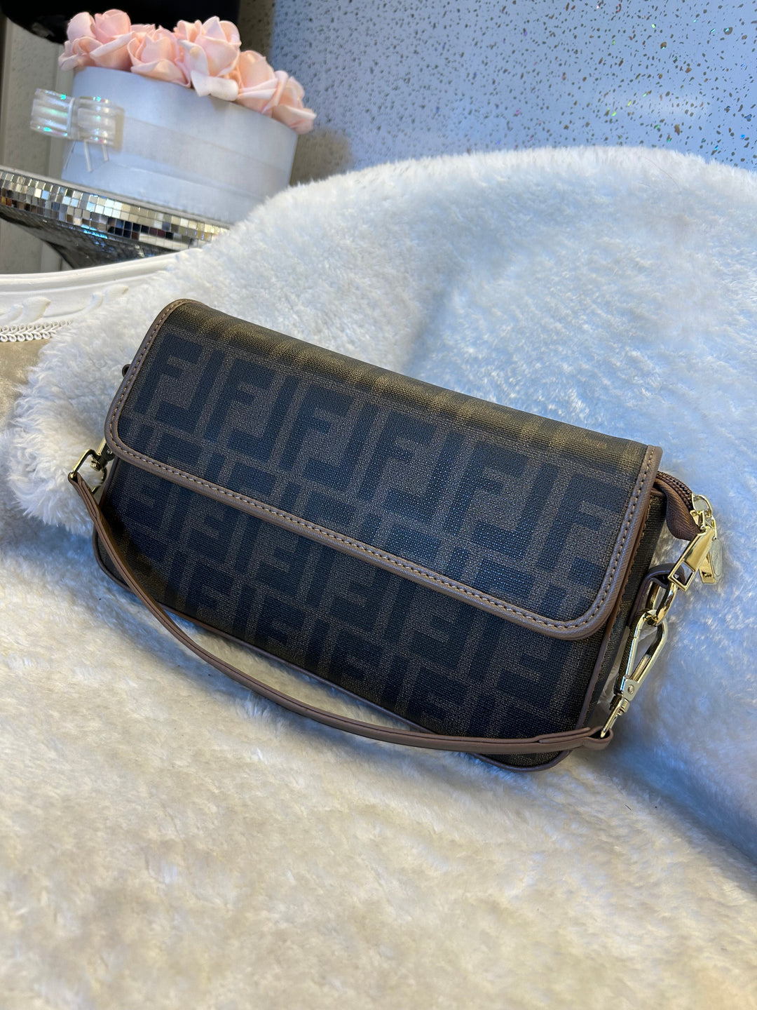 Brown handbag with shoulder strap on a textured surface