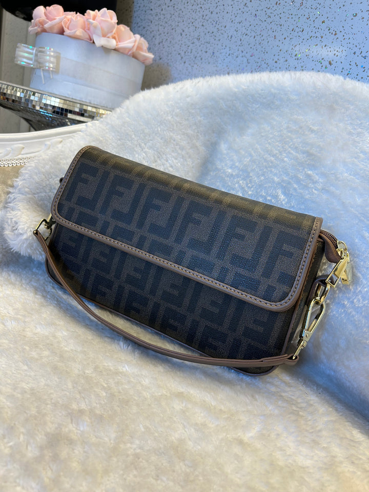 Brown handbag with shoulder strap on a textured surface