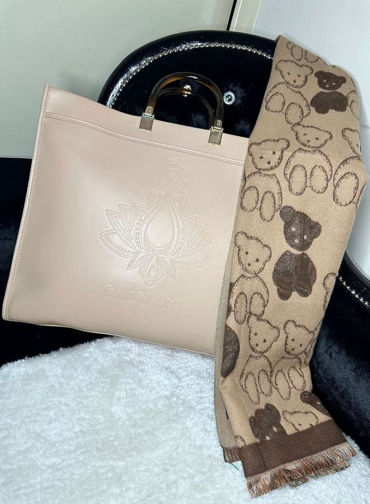 An image showing a beige handbag tote with an embossed cbs logo design, and a scarf. 