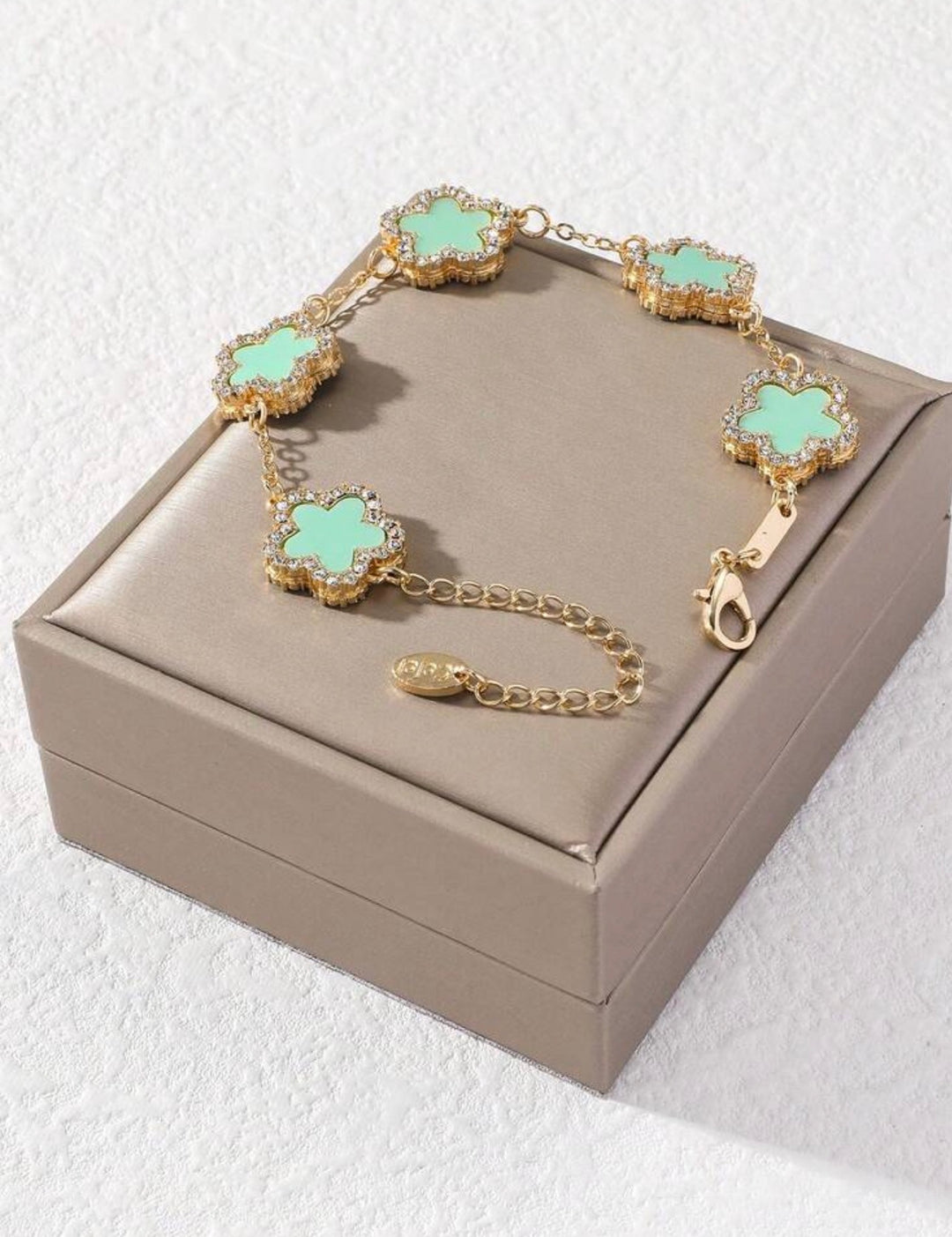     Adjustable gold bracelet with five mint clover charms and crystal detailing