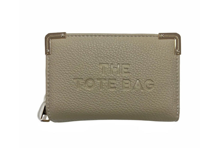 A beige synthetic tote bag with gold tone metal hardware, featuring a fold-over top with a closure, and the ‘THE TOTE BAG&