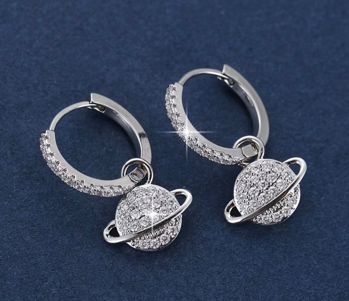 Sparkling crystal planet drop hoop earrings available in gold and silver.