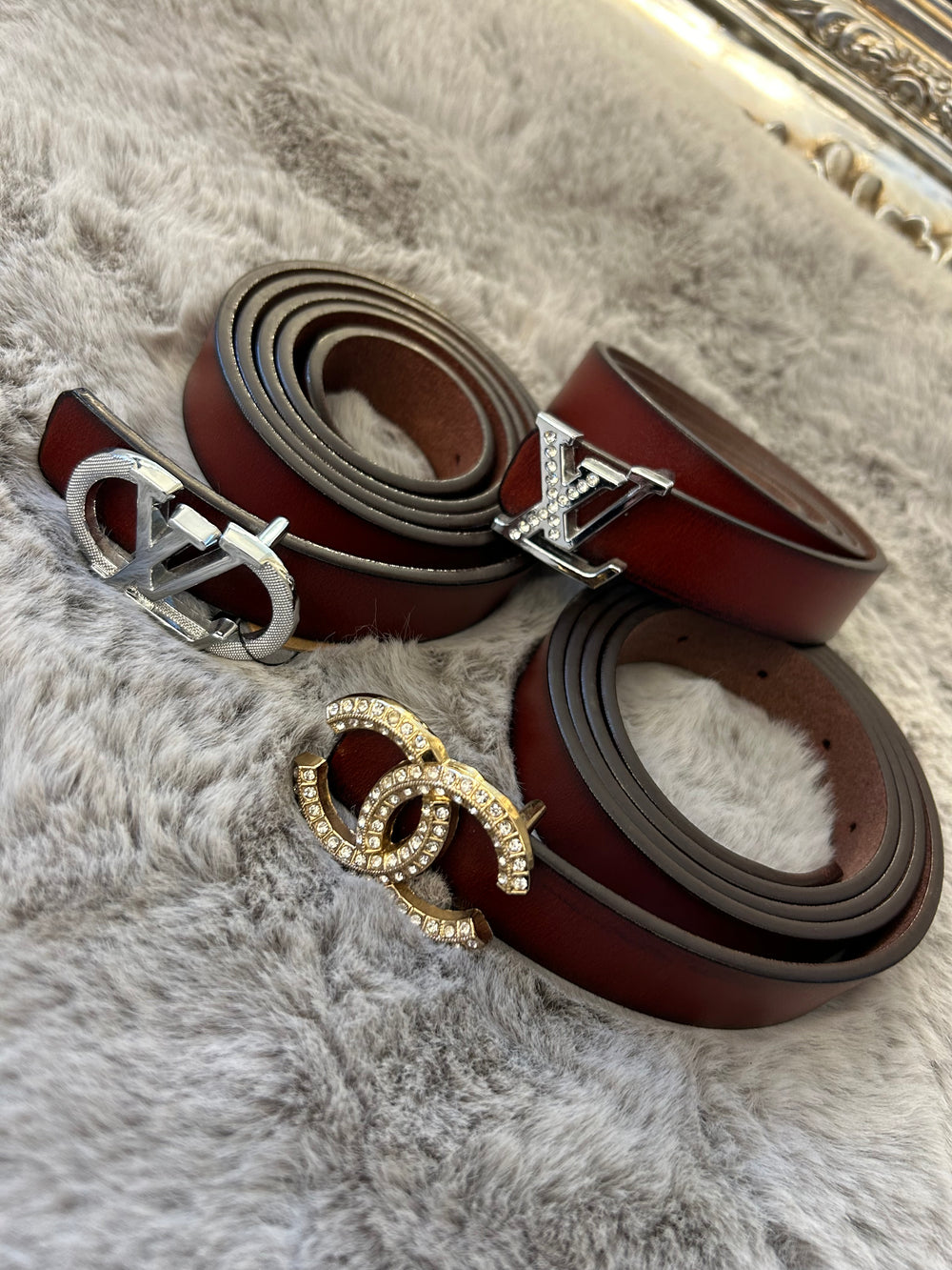 A collection of small brown belts with different buckles