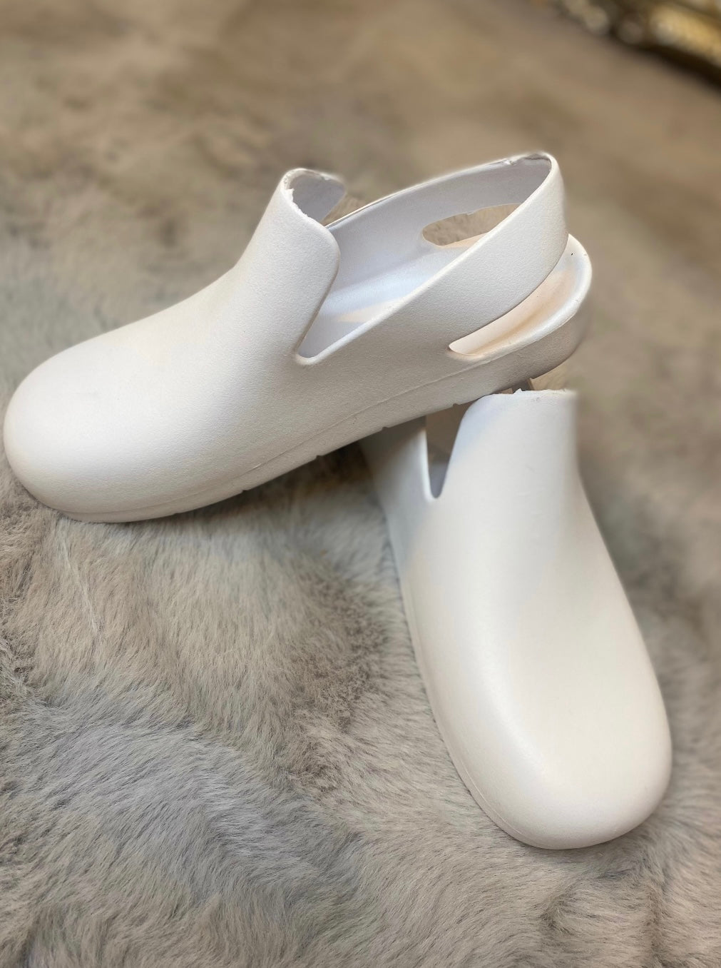 A pair of white slingback clogs 