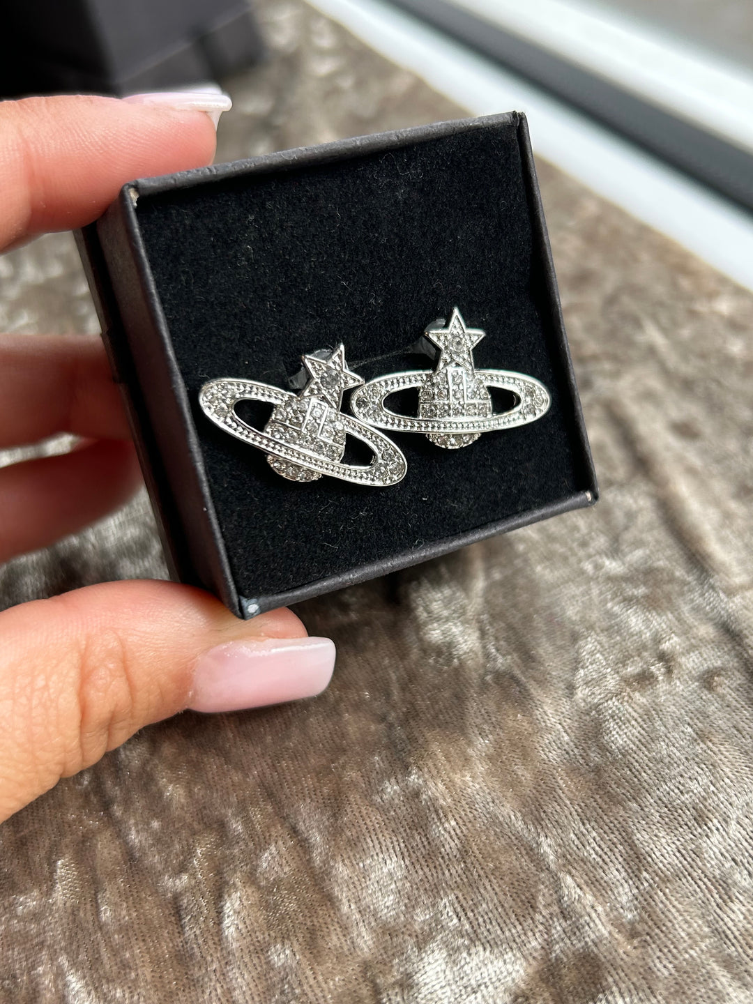 A pair of silver-colored star planet earrings 