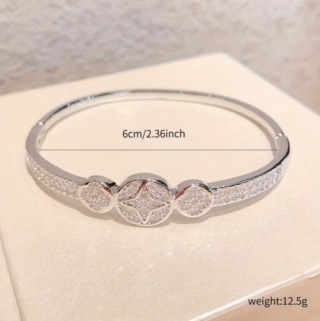 Silver crystal bangle bracelet with sparkling star and heart detail design on a silver-tone hinged cuff bracelet.