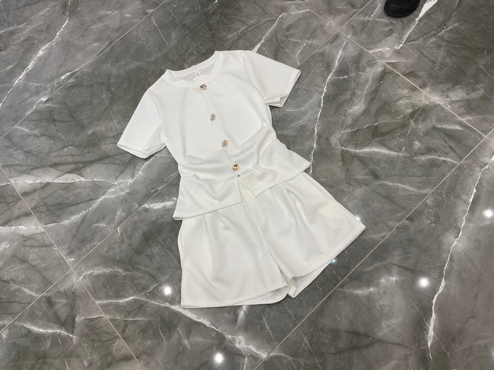 White co ord set flat lay with gold button detail top and matching shorts