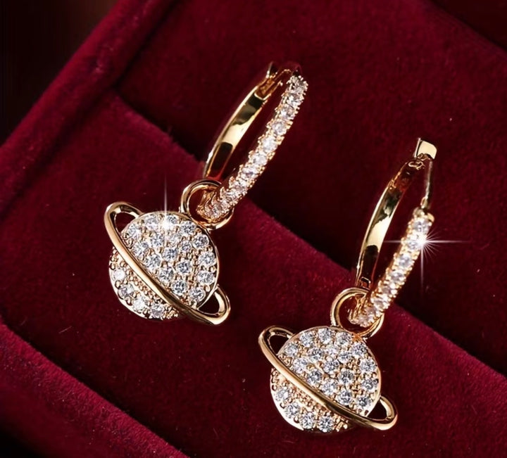 Sparkling crystal planet drop hoop earrings available in gold and silver.