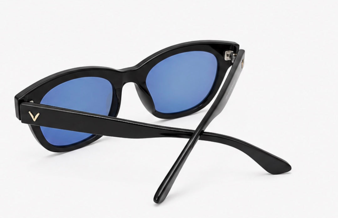 Black oversized sunglasses with glossy black frames, blue mirrored lenses and gold V detail