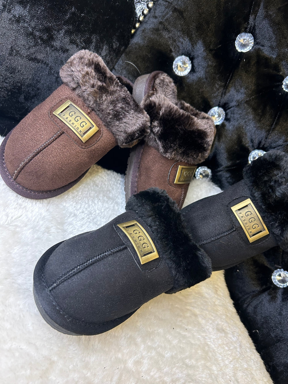 a choice of chocolate brown or black closed toe slip on faux fur slippers with gold buckle on the front