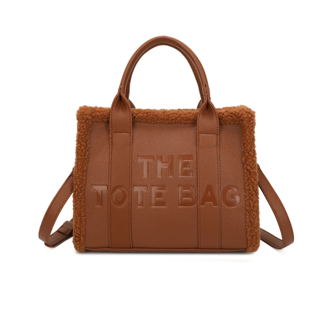 Tote bags with fuzzy edge trim, embossed with ‘The Tote Bag’ on the front in brown